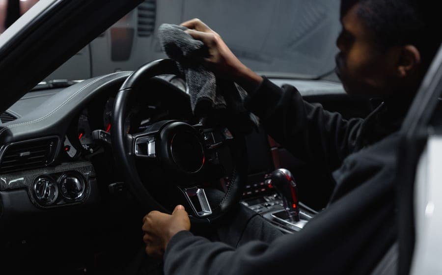 Person wiping down a car interior with a microfibre cloth