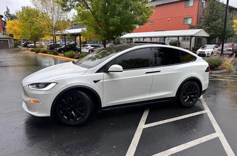 White electric SUV parked at a curb with the lower bodywork and wheels in frame