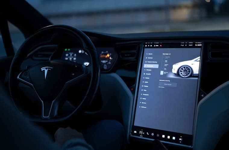 Tesla center touchscreen and steering controls photographed from the passenger side