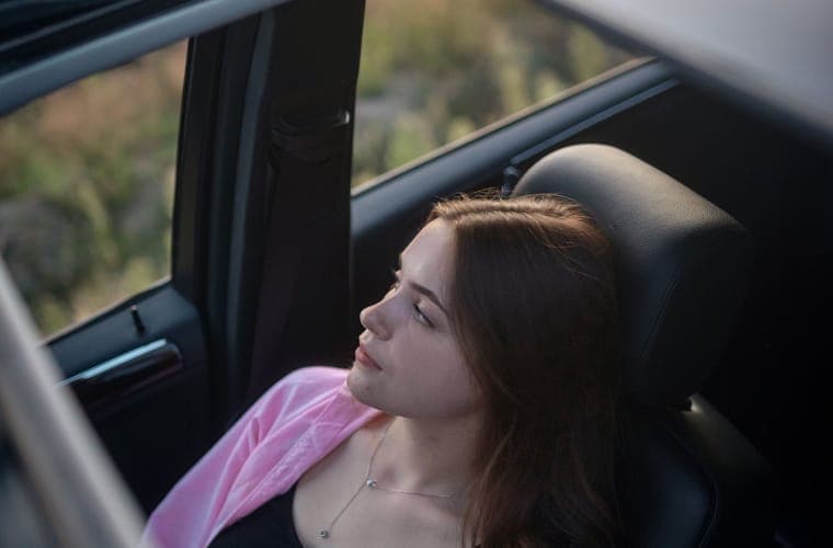 Passenger reclining in a car with the roof glass open to the sky above